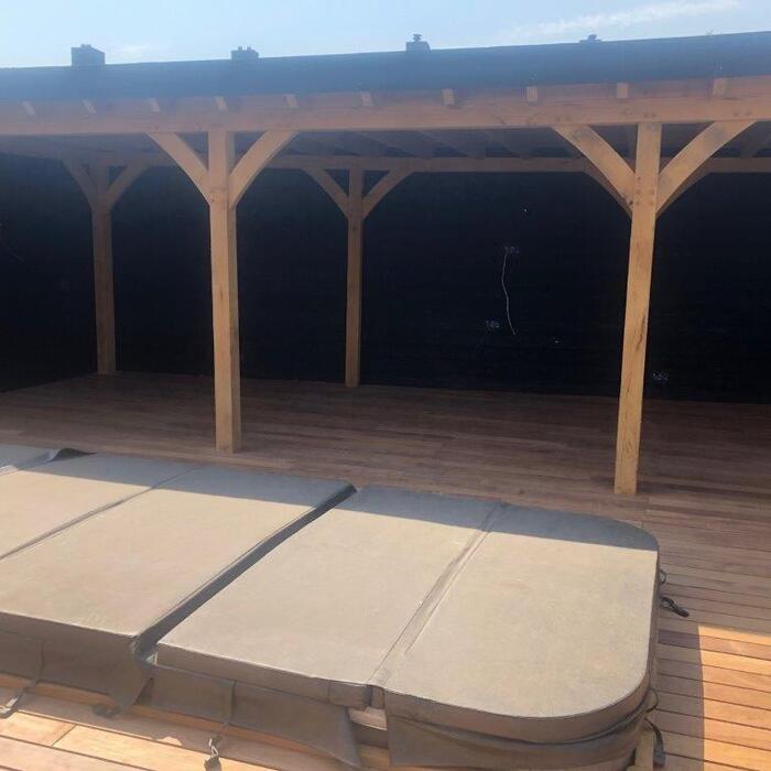 Atmospheric side view of a bespoke oak framed shelter with a seamless Ipe hardwood deck surrounding a swimming pool.