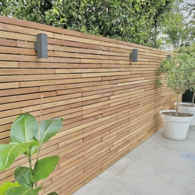 High-end 7.0 cm Ipé slatted fence featuring black EPDM backing for added depth and noise reduction. Posts are hidden for a seamless modern look.